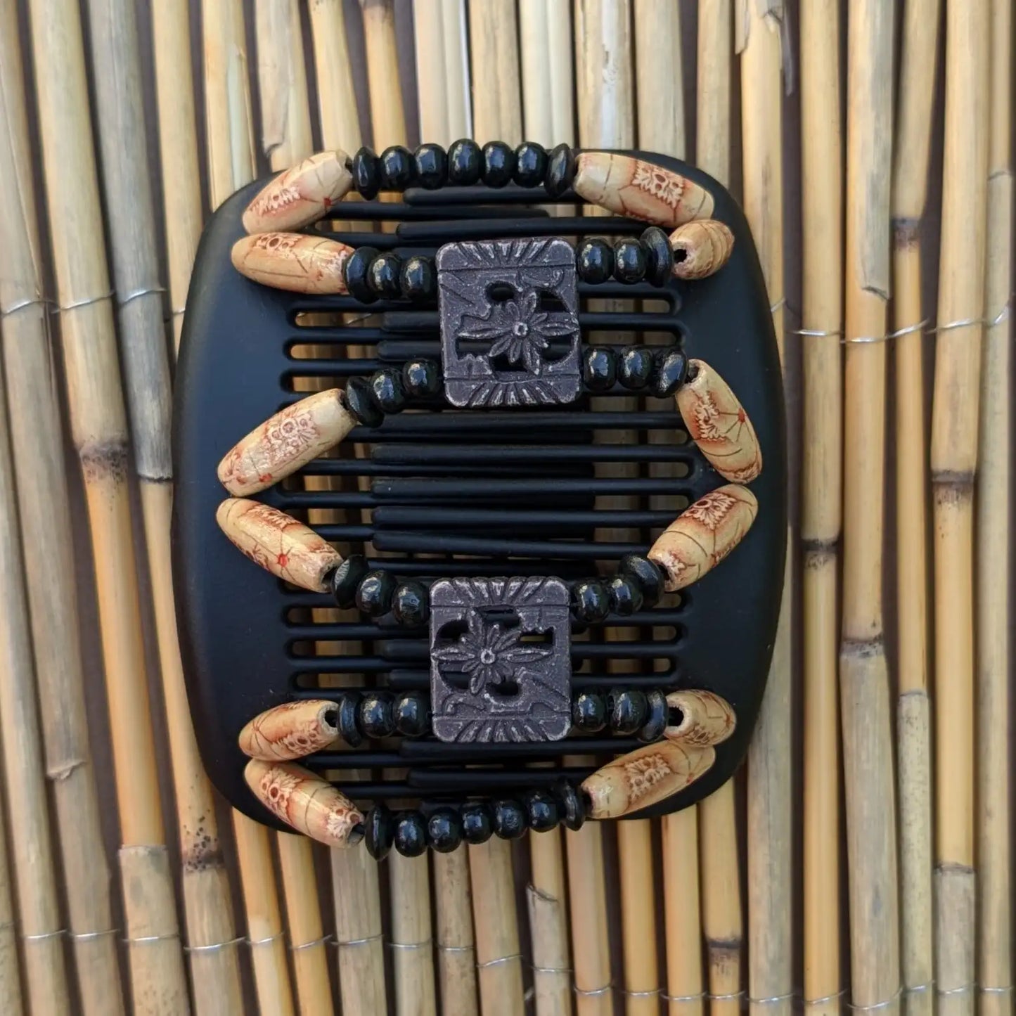 Schwarzer African Butterfly Haarkamm mit schwarzen und beigefarbenen Holzperlen mit roten Mustern und quadratischen Zierperlen in Blumenform– flexibler Haarschmuck für Hochsteckfrisuren.