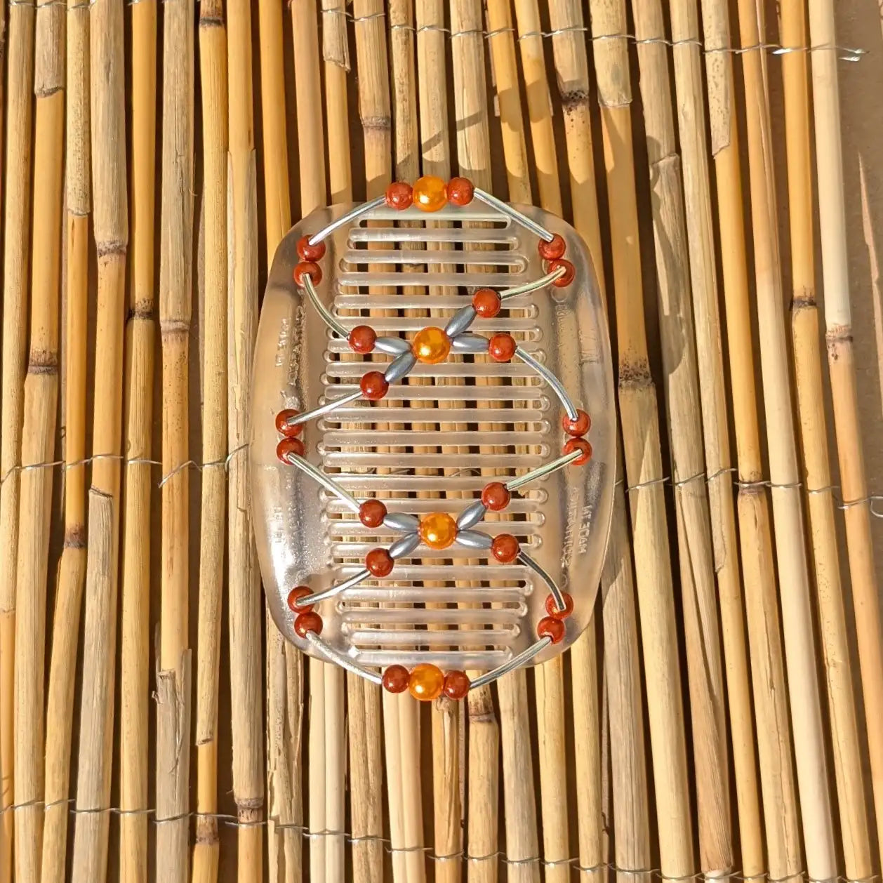 Durchsichtiger African Butterfly Haarkamm mit orangen und silbernen Kunstperlen mit feinen Metallstäben - flexibler Haarschmuck für Hochsteckfrisuren.
