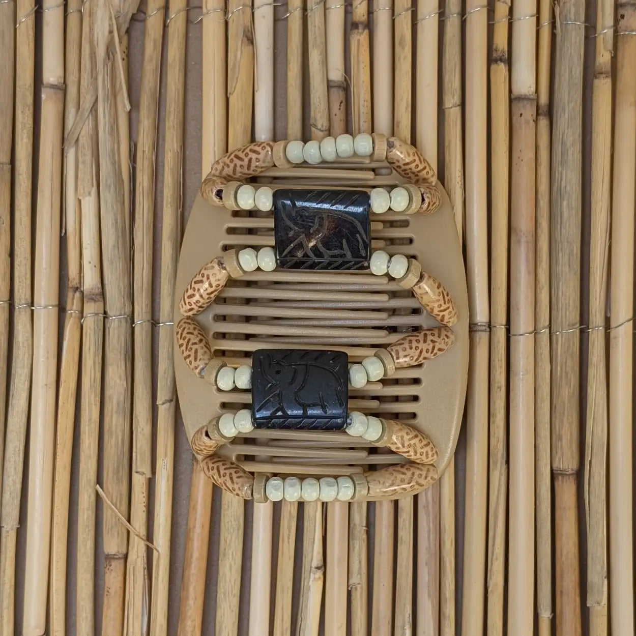 Beiger African Butterfly Haarkamm mit hell gemusterten und weißen Holzperlen mit Elementen aus Horn in der Mitte - flexibler Haarschmuck für Hochsteckfrisuren.