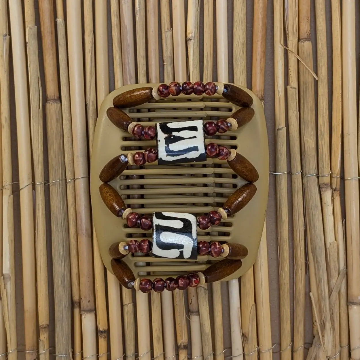 Beiger African Butterfly Haarkamm mit braunen und rötlichen Holzperlen mit Elementen aus Horn in der Mitte - flexibler Haarschmuck für Hochsteckfrisuren.