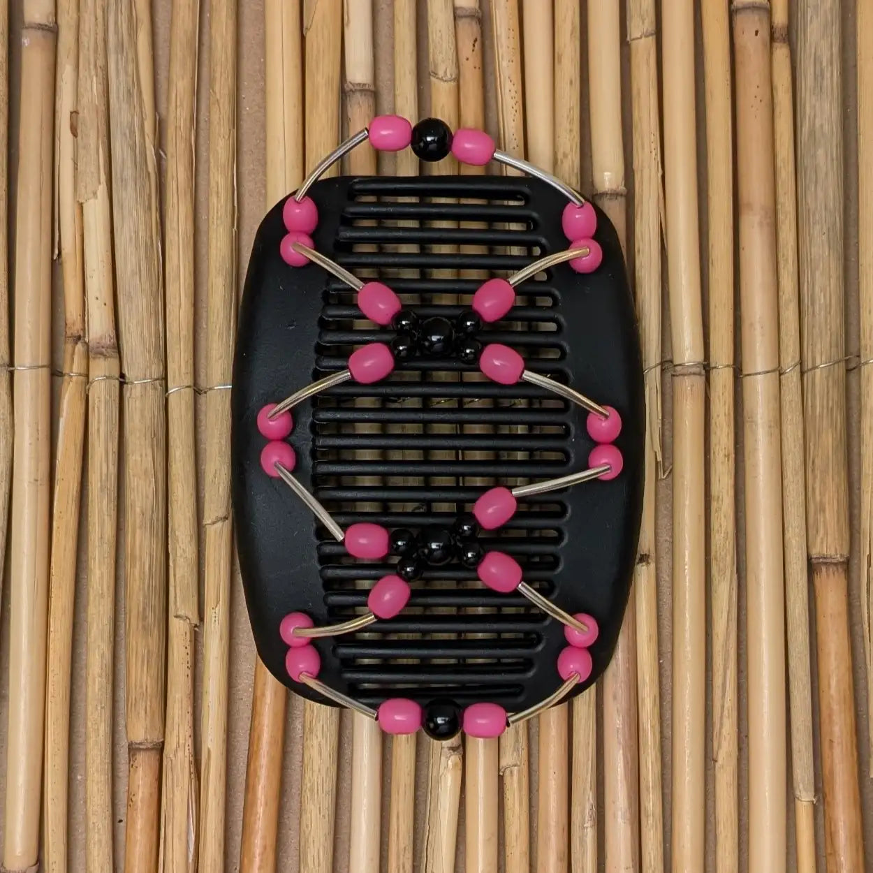 schwarzer Kamm mit pinken und schwarzen Kunstperlen die mit silberfarbenen Stäben verbunden sind