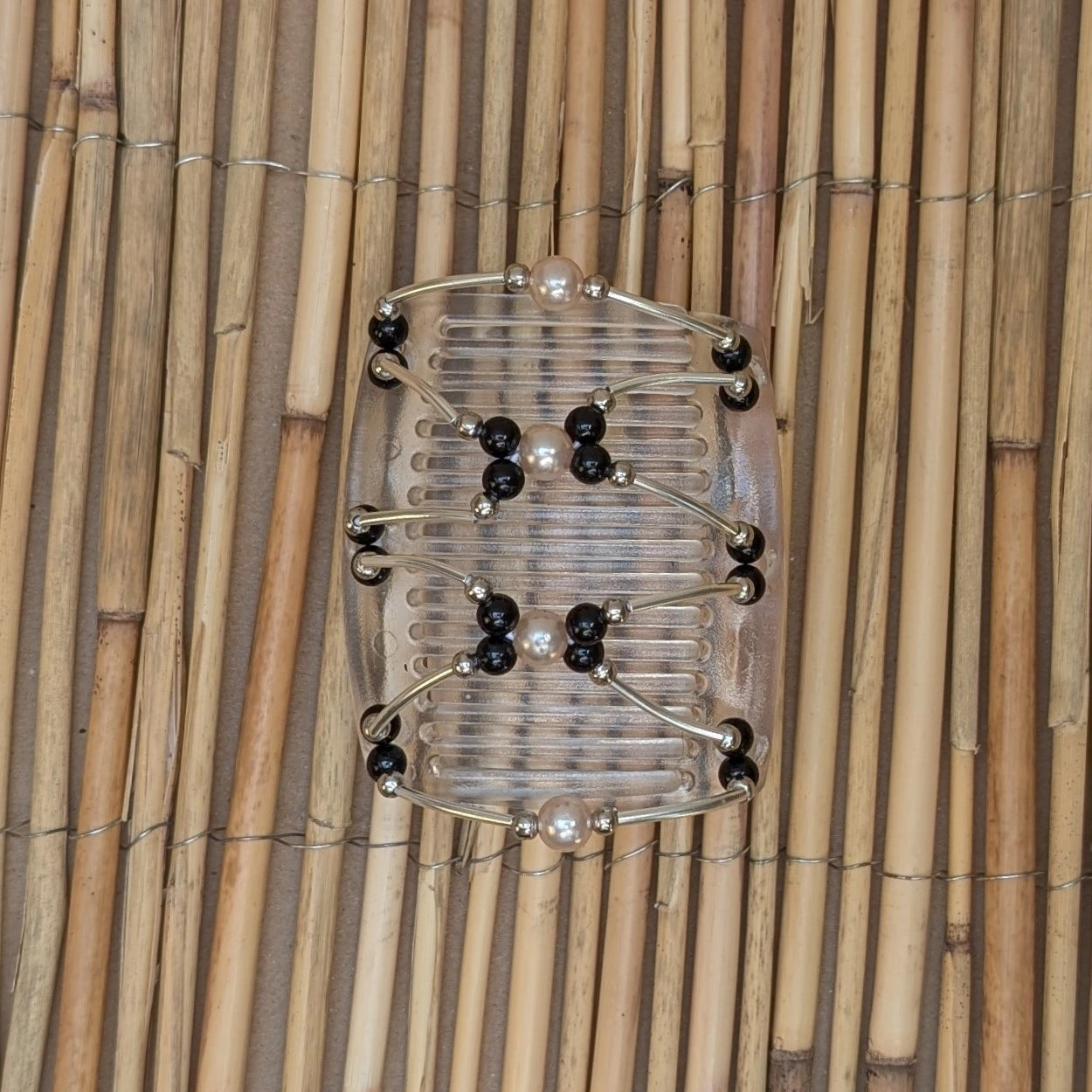 Durchsichtiger mittelgroßer African Butterfly Haarkamm mit schwarzen und cremefarbene Kunstperlen mit feinen Metallstäben - flexibler Haarschmuck für Hochsteckfrisuren.
